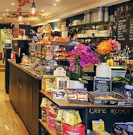 The Cafe Roma counter — fresh flowers, pastries and the blackboard coffee list