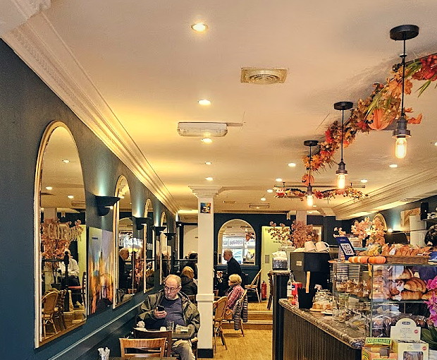 Inside Cafe Roma — the teal wall, arched gold mirrors and pendant lights